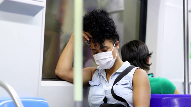 非裔美国妇女在疫情期间乘坐地铁查看手机视频素材
