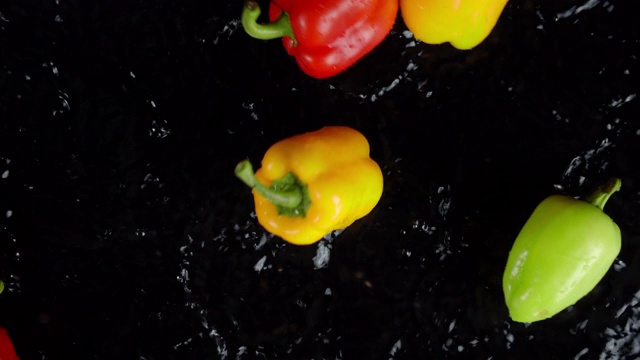 不同颜色的甜椒落到水花上。视频素材