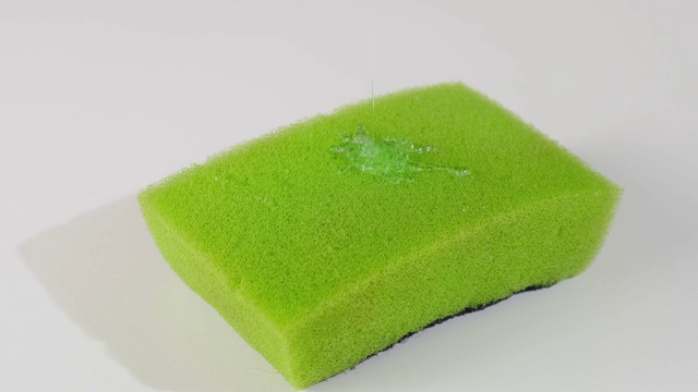 超宏近距离拍摄的黄色海绵的盘子，并以绿色凝胶的形式注入清洁剂。近距离视频素材