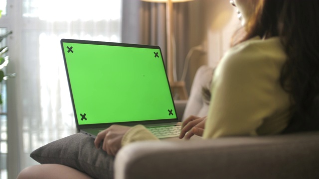 坐在沙发上使用绿色屏幕笔记本电脑的女人视频素材