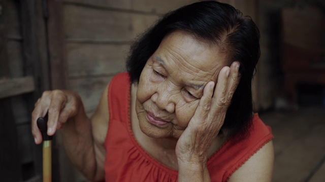 泰国老妇人在圆领无袖领口头痛和担心紧张的脸在木制的家视频下载