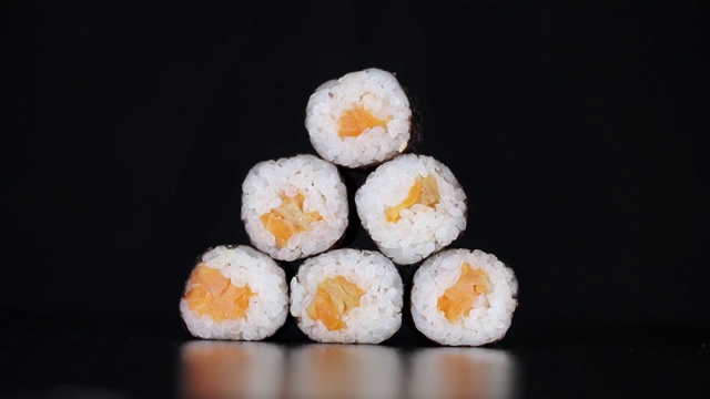 寿司以金字塔的形式在黑色的背景上旋转。特写镜头。日本食物中的鲑鱼。视频素材