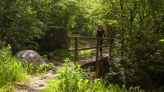 适合的女人徒步在户外的自然横跨小溪上的一座桥视频素材