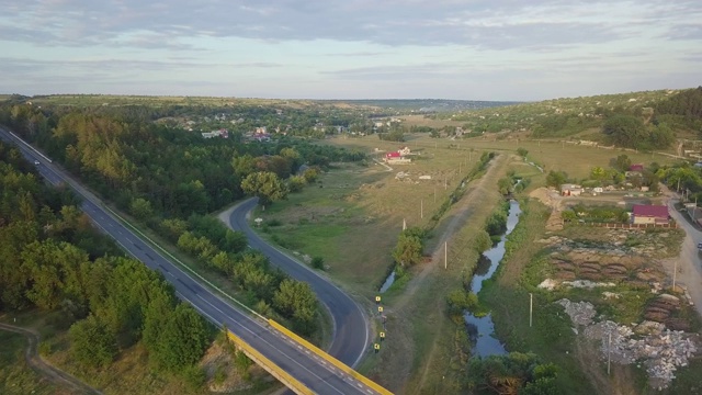 鸟瞰图高速公路通过绿色的田野在一个夏天的阳光灿烂的一天。在草地和乡村田野之间有沥青高速公路的4k镜头景观。无人机拍摄视频。视频素材