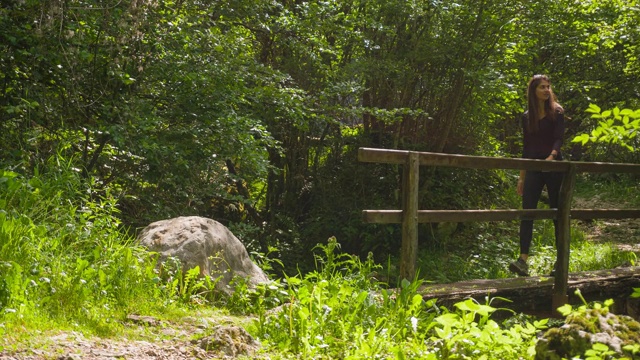 一名年轻女子正越过山涧上的一座小木桥视频素材