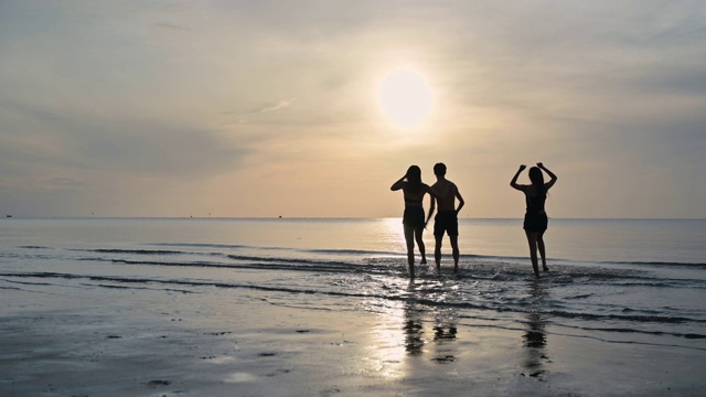 一群年轻的亚洲朋友在海滩上玩耍和跑步视频素材