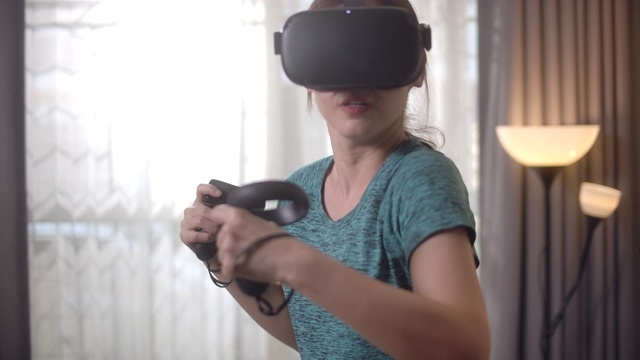 亚洲女性使用VR头盔在家玩游戏视频素材