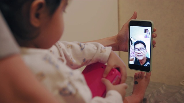 手持拍摄可爱的蹒跚学步使用智能手机与祖父母视频通话视频素材