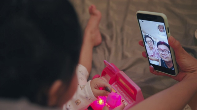 手持拍摄可爱的蹒跚学步使用智能手机与祖父母视频通话视频素材