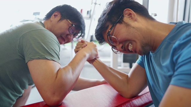两名亚洲男子在扳手腕比赛，其中一人咬了另一人的手而作弊视频素材