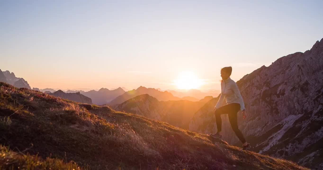 健康的女性运动员保持健康的生活方式，在日落时在岩石小径和草坡的山上徒步旅行视频下载