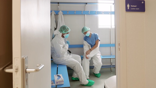 两名医生在医院更衣室脱下防护装备视频素材