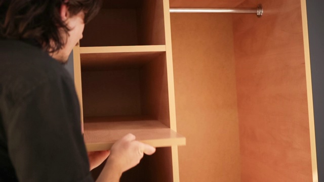 一名男子在放置康乃馨的橱柜中插入书架。视频下载