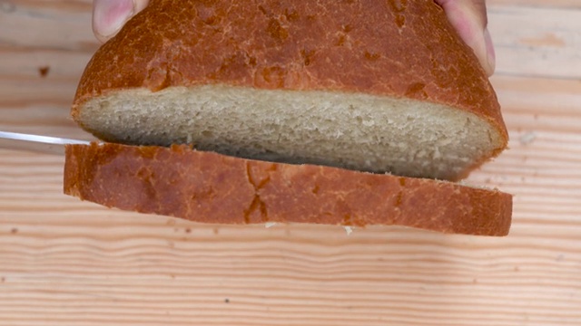 用刀在木板上切一片白面包。从以上观点。特写镜头视频素材