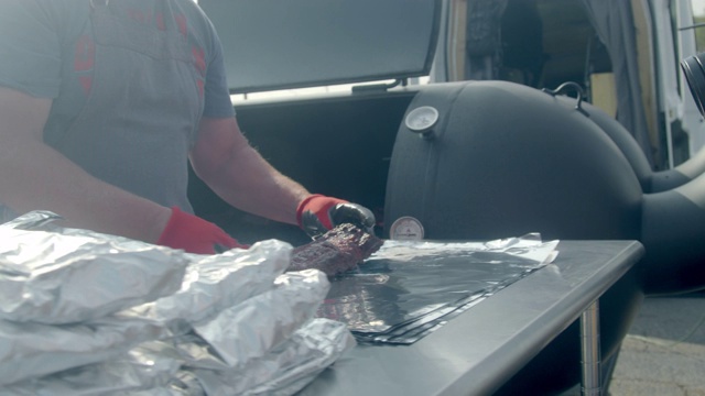 烧烤pitmaster拉一架多汁的烟熏猪肉婴儿背排骨从一个商业烟熏和铝箔包裹服务视频素材