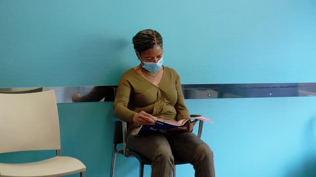 成熟的女人戴着口罩在医院接待处等候视频下载