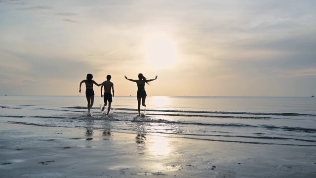 一群年轻的亚洲朋友在海滩上玩耍和跑步视频素材