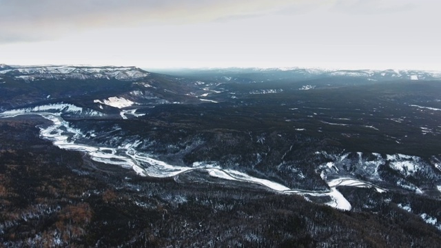 在加拿大阿尔伯塔省的一片茂密的黑森林里，一架无人机拍摄到了一条冰冻的蜿蜒的特察河视频素材