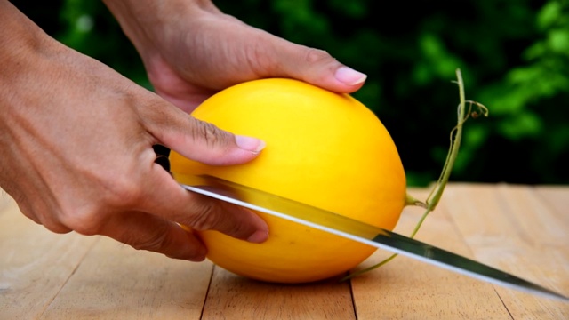 这个人用刀在木板上劈开甜瓜视频素材