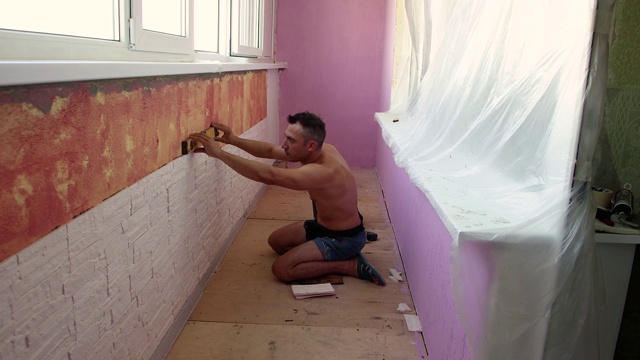 一个年轻人正在往墙上铺瓷砖视频素材