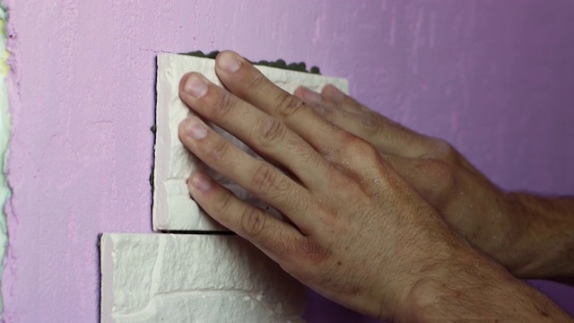 特写的手把瓷砖压在墙上。视频素材
