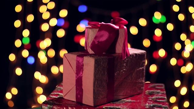包装精美的粉红色丝带礼物。礼物在散景灯或发光的花环背景。特写,旋转。圣诞节或新年。慈善组织的概念。节日的气氛视频素材