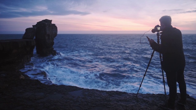 一个摄影师在多塞特海岸的波浪海洋上的美丽的岩石的自然照片，英国-中等拍摄视频下载