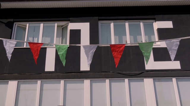 红色，绿色，白色的花环缎子旗在城市节日中迎风飘扬视频下载