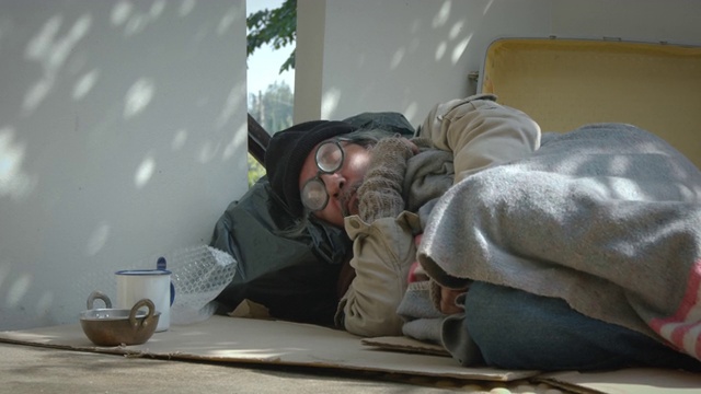 一个无家可归的老人躺在人行道上视频下载