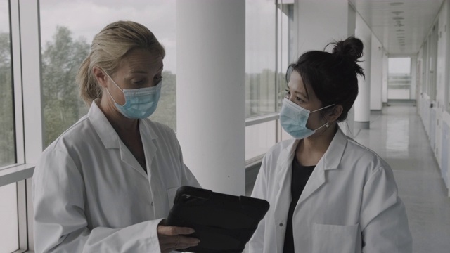 女医生在医院走廊开会讨论数字平板电脑技术的测试结果视频素材