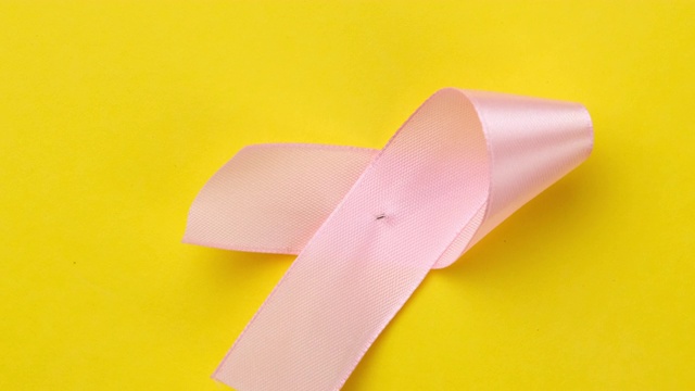 黄色背景上的粉色丝带，是乳腺癌意识的象征视频下载