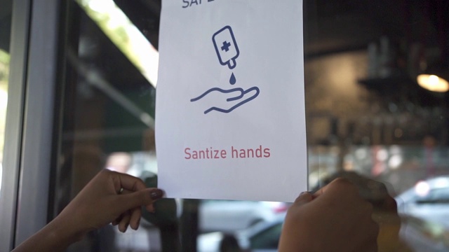 女服务员在她的咖啡店的玻璃门上贴了一个牌子，上面写着洗手是一种义务视频下载