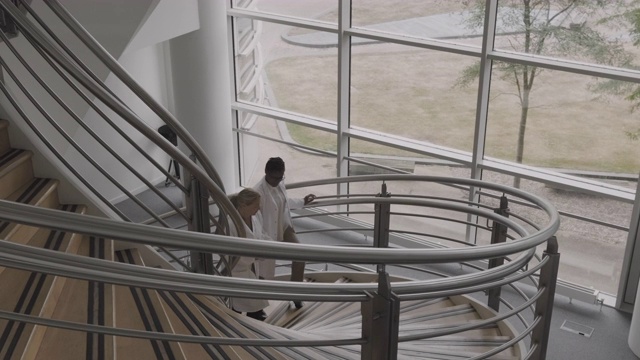 两名女医生走在医院的楼梯上讨论医疗保健的进展视频素材