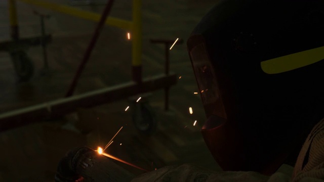 员工在特殊面罩下用火花在黑暗中焊接管道视频下载