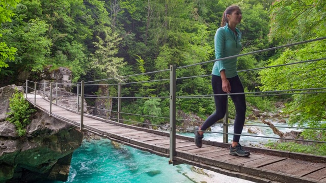 年轻的女性游客徒步穿越一座横跨山涧峡谷的木桥视频素材