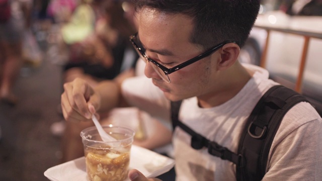 男子吃泰式甜点，软豆腐在热姜糖浆在当地街头小吃视频素材