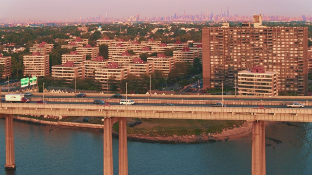 鸟瞰图的比彻斯特住宅区在皇后区与曼哈顿在Throgs颈桥在日出的遥远的背景。无人机视频片段与向前摄像机运动视频素材