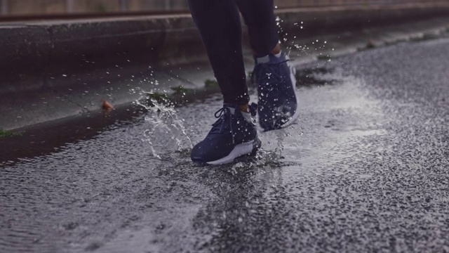 慢动作特写的运动鞋在雨中踩水坑视频素材