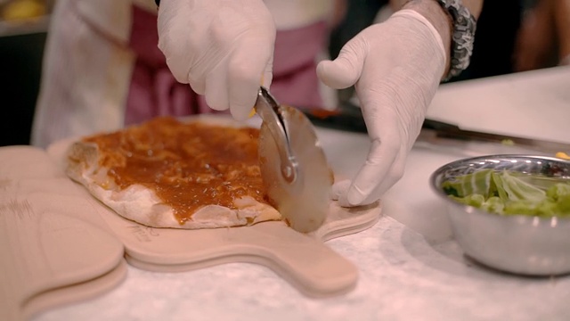 厨师用一把特殊的圆刀切披萨。在咖啡馆做饭视频素材