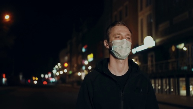 戴着面具的人走在夜间城市街道灯光市场新冠肺炎4K。视频下载