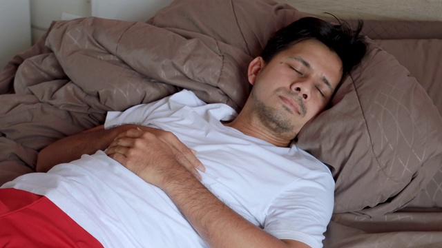 年轻的亚洲男人睡在床上视频素材
