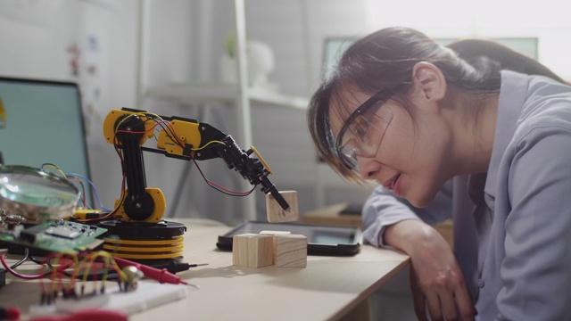女工程师在他的车间里看着创新技术机械机器人手臂，她用数字平板电脑用手控制机器人手臂视频下载