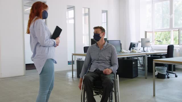 一位女士在办公室和一位残疾同事聊天视频素材