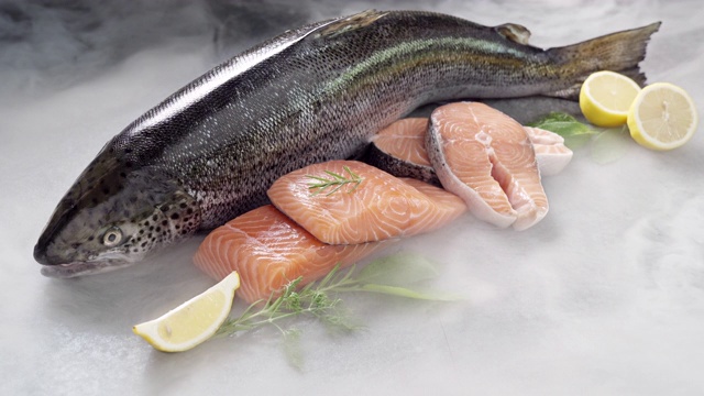 4K超高清:鲑鱼及其鱼片在黑色背景和冰冻的冰烟。新鲜豪华海鲜和菜单食谱零售市场概念。视频下载