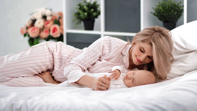 穿着睡衣的可爱女人看着熟睡的孩子享受快乐的母亲身份。4k Dragon RED摄像机视频下载