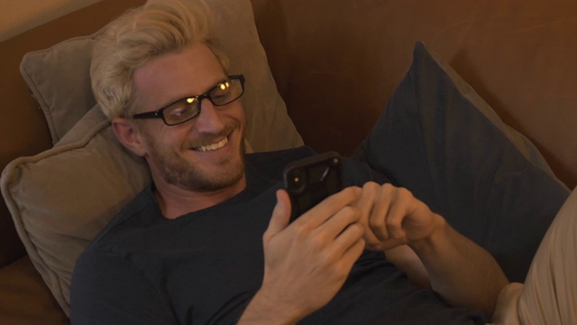 男人晚上躺在沙发上看他的手机视频素材