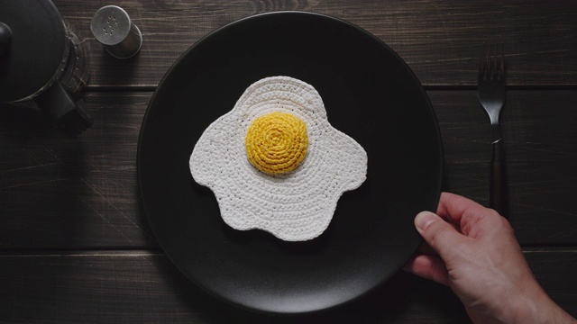 在桌子上的盘子里编织着煎蛋。深色木质表面。合成食品。前视图。视频下载
