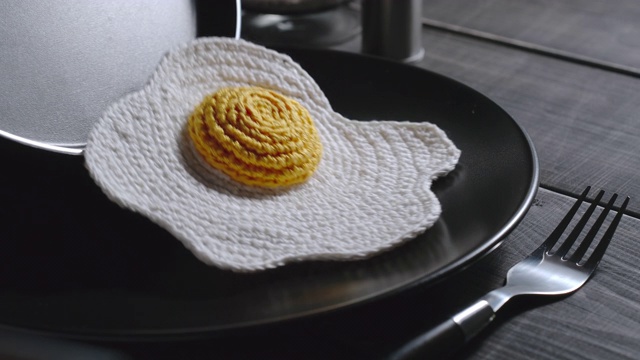 编织的煎蛋被放在盘子里。合成食品。深色木质表面。近距离视频下载