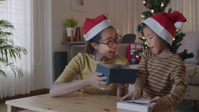 快乐的亚洲家庭与母亲和女儿一起打开圣诞礼物礼盒在假日在家视频素材