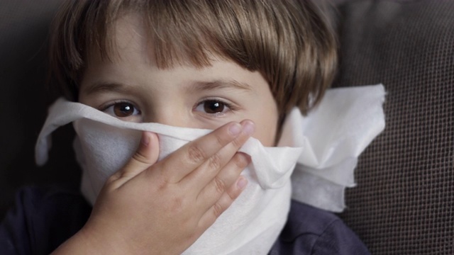 不健康的生病男孩的肖像与餐巾关闭她的鼻子从过敏或鼻炎。不幸的生病的孩子从流鼻涕和打喷嚏和擤鼻涕。儿童感冒流感疾病。视频素材